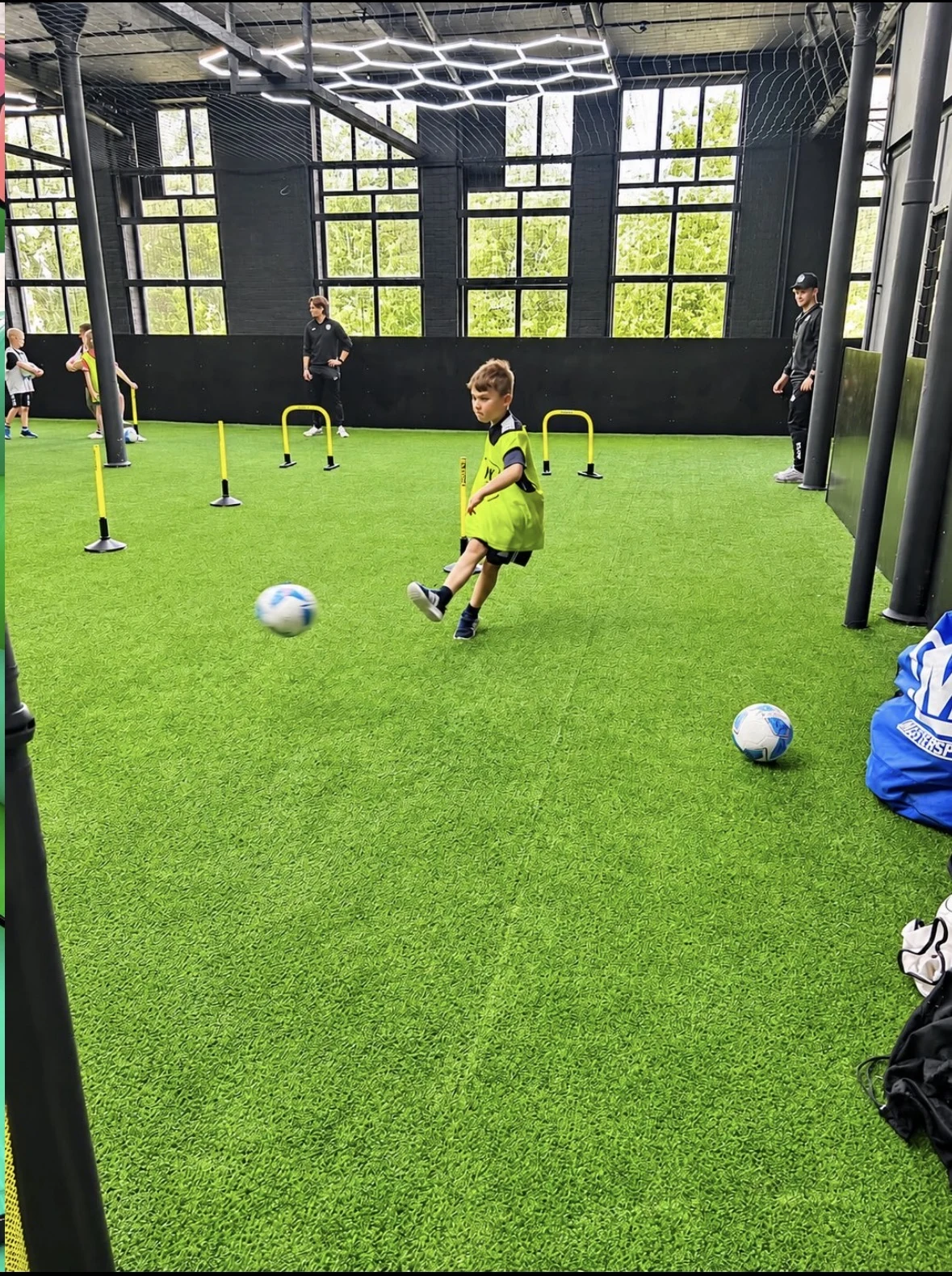 Child striking a football during a UK Sports birthday party session in the arena
