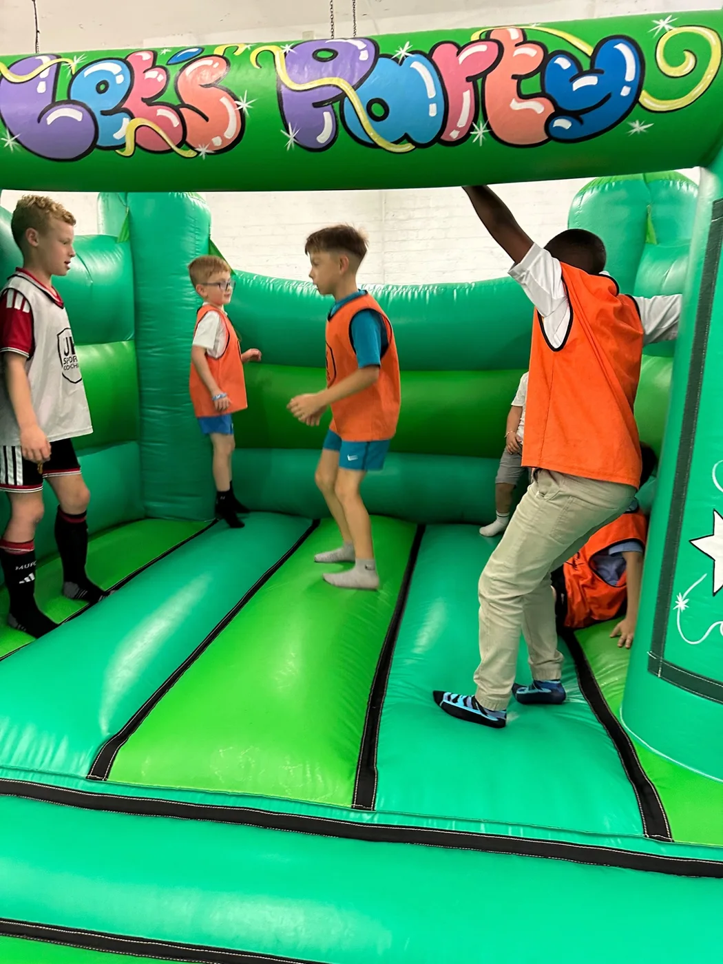 Children enjoying a bouncy castle during a UK Sports Coaching Ltd birthday party