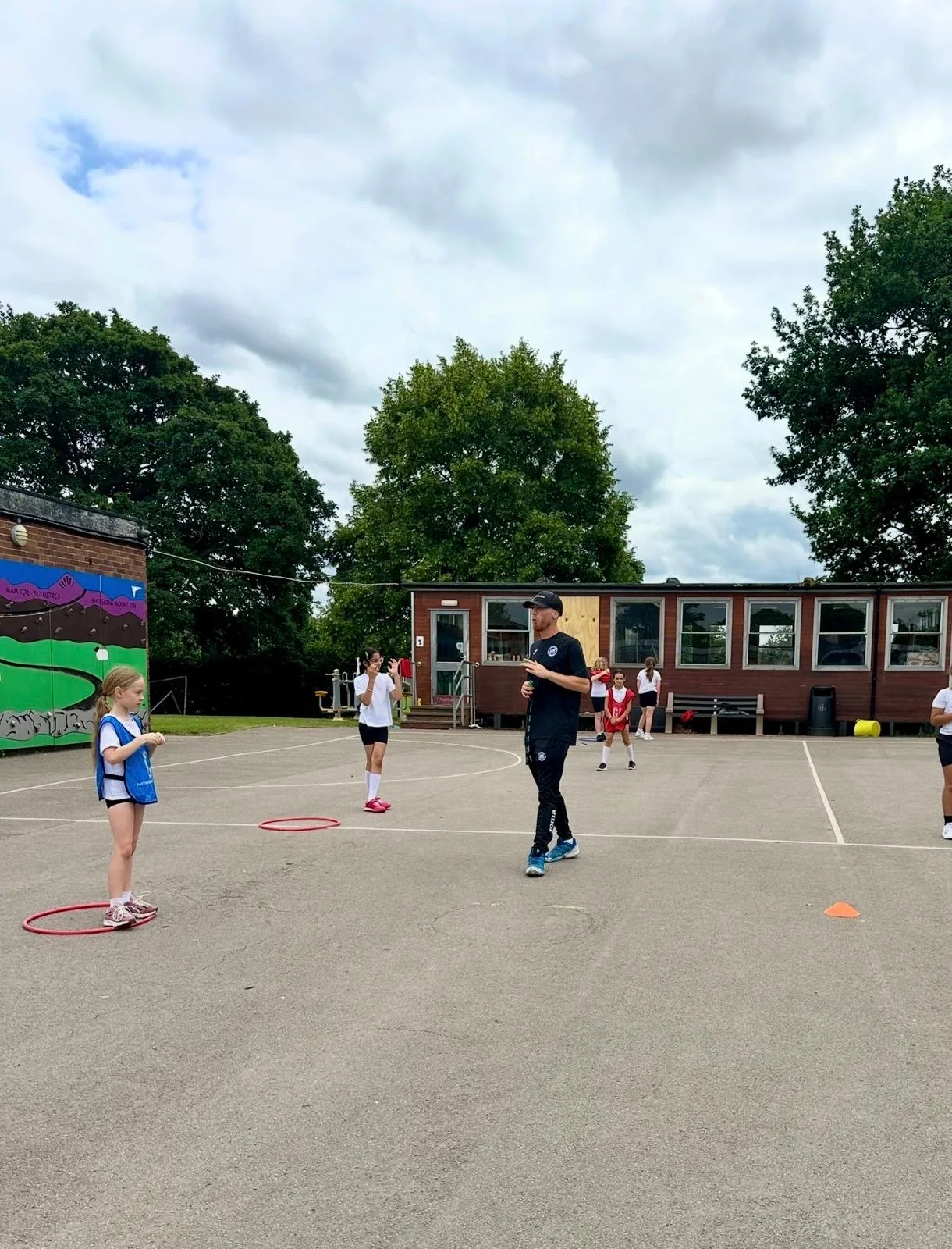 UK Sports coach leading an outdoor PE session with children on a school playground