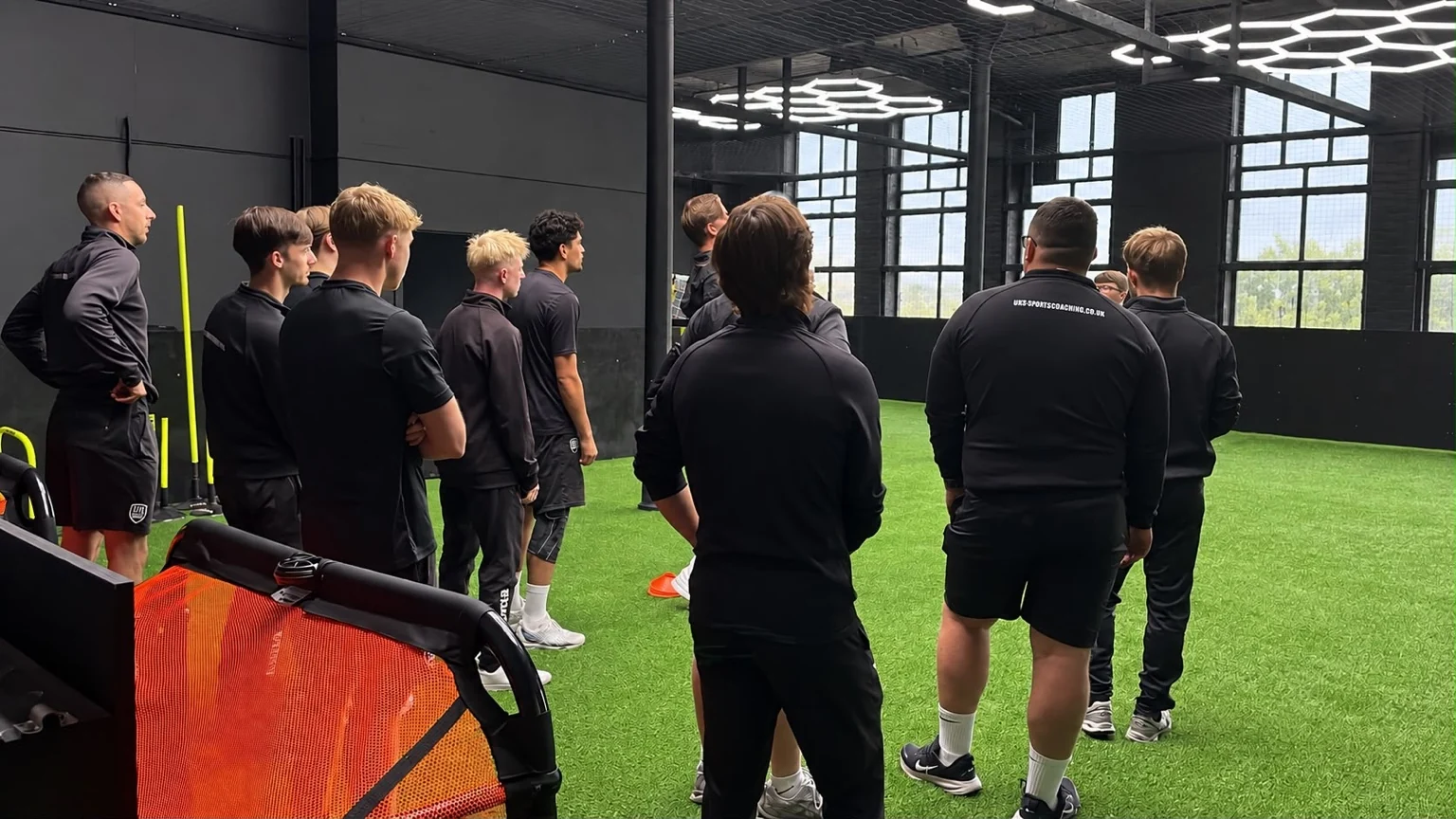 UK Sports coaching staff gathered together during a training briefing in the indoor Arena